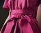 A closeup of a magenta dress with a bow belt and hidden pockets. Trendy color of 2023 Viva Magenta.. AI generation