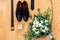 Closeup of male accessorieson wooden background. Top view of belt, shoes, floral corsage, golden rings, wedding concept