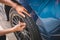 Closeup male automotive technician removing tire valve nitrogen cap for tire inflation service at garage or gas station. Car