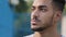 Closeup male face outdoors. Serious pensive millennial arabic hispanic guy with brown eyes and beard looking away