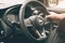 Closeup male hand driving a car with interior luxury dashboard and steering wheel