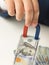 Closeup of male hand holding magnet and pulling money from stack