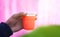 Closeup of a male hand holding up a glass of smoothie with red color - Image