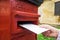 Closeup on a male hand putting a letter in a red letterbox. Concept of vintage type of communication.