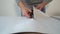 Closeup male hands cut new bended wallpaper roll with scissors on table indoor