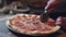 Closeup of male hands cuting pizza with round knife