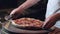 Closeup of male hands cuting pizza with round knife