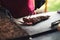 Closeup of male hands slicing and serving piece of grilled beef meat on black kitchen board. Celebration, party