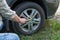 Closeup of male hands using a wrench for a car tire. Wheel replacement after an accident in a sunny day. Show car repair by car ow