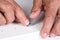 Closeup of a man assembling a DIY piece of furniture. The person is inserting a shelf support pin into a pre-drilled hole