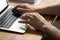 Closeup man hands typing on modern laptop at office desk