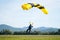 Closeup of a man parachuting near the ground with a yellow parachute during daylight