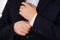 Closeup man\'s arm wearing suit, adjusting cufflinks using hands, men getting dressed concept