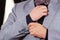Closeup man\'s arm wearing suit, adjusting cufflinks using hands, men getting dressed concept
