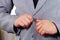 Closeup man\'s chest area wearing formal suit and tie, adjusting jacket buttons using hands, men getting dressed concept