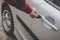 Closeup of a man\'s hand inserting a key into the door lock of a car. Unrecognizable white man opens vehicle door by key. Casually