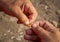 Closeup of man`s hands baiting a fishing hook with pasta pieces for carp