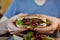 Closeup of man`s hands holding vegan chickpea and bean burger with fresh greens