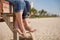 Closeup of man`s and woman`s feet. People sitting on the wooden deck on the beach.