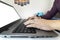 Closeup of a man typing on a laptop keyboard