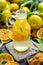 Closeup of mandarine water in a bottle on a table with dry citruses and leaves