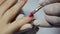 Closeup manicurist applies a red gel nail polish. Woman in beauty spa salon doing manicure