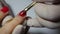 Closeup manicurist applies a red gel nail polish. Woman in beauty spa salon doing manicure
