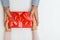 Closeup of a mans hand giving a red box with a gift to a woman