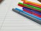 Closeup of many pens with different colors laying on the top of the white empty notebook with lines for better note taking in