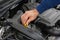 Closeup of mechanic hands checking motor under the hood in the broken car. Repairing of the vehicle concept. Automobile service