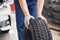 Closeup of mechanic hands pushing a black tire in the workshop