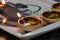 Closeup of melted candles on a kitchen tray with a kettle pattern, two of them still lit