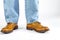 Closeup of Mens Legs on Brown Oxford Brogue Shoes. Posing in Blue Jeans Against White Background