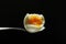 Closeup of metal spoon and just cooked soft boiled egg on it, black background