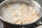 Closeup of metal stewpan with boiling water and dumplings