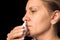 Closeup of middle aged woman dripping nasal drops in nose. Female sprays at home to treat cold, flu or allergy. Health care