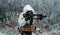 Closeup military man in white camouflage uniform with hood and aims of the machinegun. Horizontal photo side view