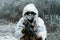 Closeup military man in white camouflage uniform with hood and machinegun. Horizontal photo