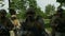 Closeup of military team walking in one formation on patrol outside in a rural area while holding their guns