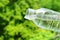 Closeup mineral water dropping from plastic bottle with blurry green foliage in background