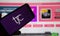 Closeup of mobile phone screen with logo lettering of tele shopping channel tjc, blurred website background