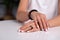 Closeup model hands with manicure, white nails, black ring with stone, bracelet made of shiny black beads, red, beige braided