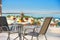 Closeup of modern patio with fruits, wine, table, chairs on roof top terrace of luxury sea view resort with blue sky copy space