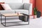 Closeup of modern wooden and metal coffee table next to stylish grey couch in trendy living room