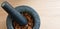 A closeup of a mortar full of almonds with a pestle on top