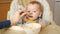 Closeup of mother feeding porridge to her baby son with spoon. Concept of parenting, healthy nutrition and baby feeding