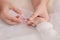 Closeup mother hand holding nail clipper cutting newborn baby nails on tiny fingers while adorable infant sleeping, keep clean