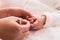 Closeup mother hand holding nail clipper cutting newborn baby nails on tiny fingers while adorable infant sleeping, keep clean