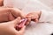 Closeup mother hand holding nail clipper cutting newborn baby nails on tiny fingers while adorable infant sleeping, keep clean