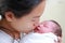 Closeup mother kissing infant baby in her arms in hospital after delivery room